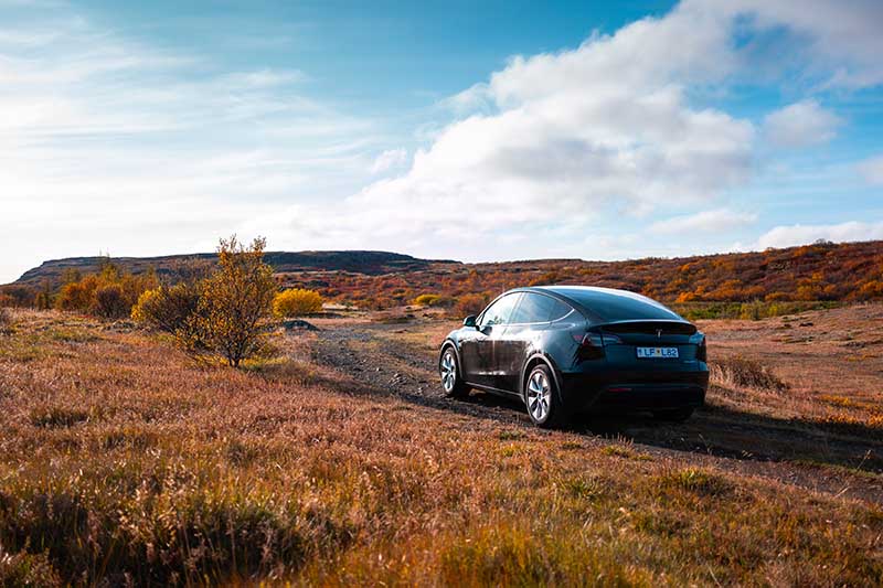Tesla Y driving on gravel road in Iceland autumn colors