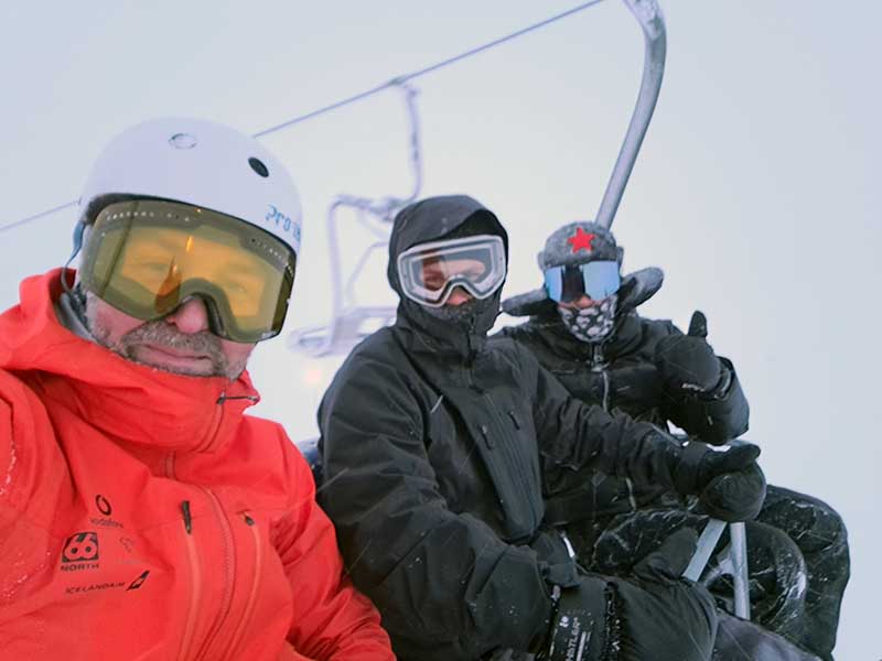 Group of three snowboarders riding the chair lift in Hlidarfjall