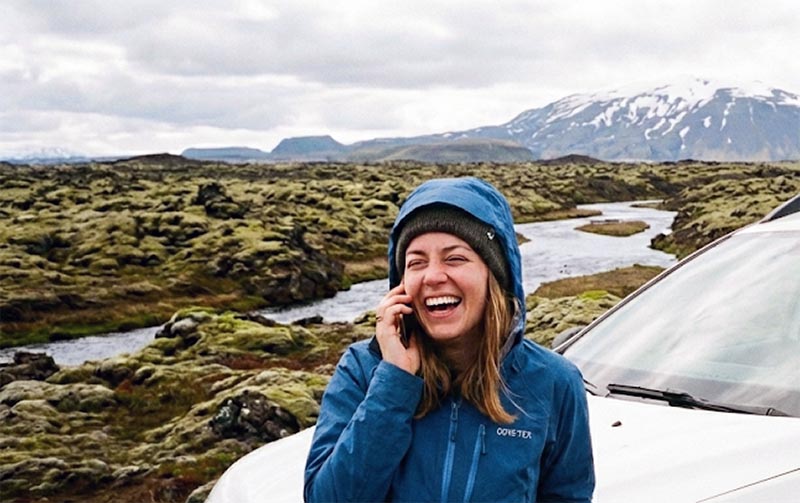 Tourist in Icelandic nature talking on a mobile phone next to a 4x4 SUV