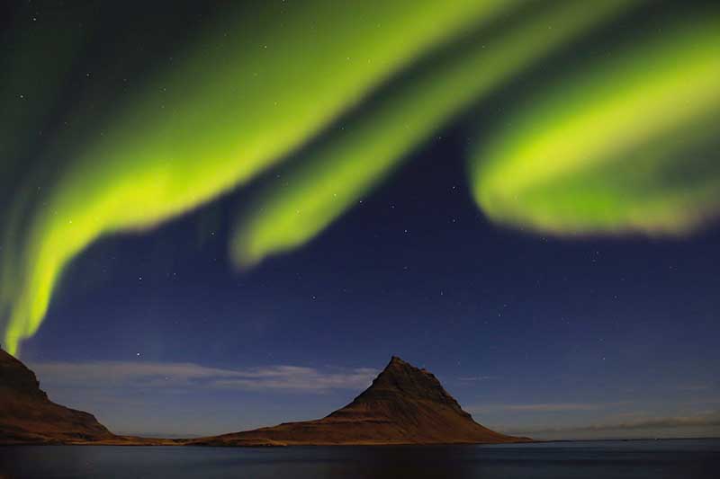 The Northern Lights dancing above Mount Kirkjufell in Iceland