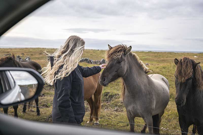 Couple standing beside a rental car from Holdur car rental in Iceland