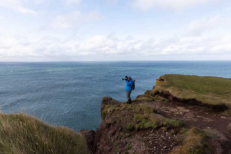 Man with camera near sea cliffs in Iceland