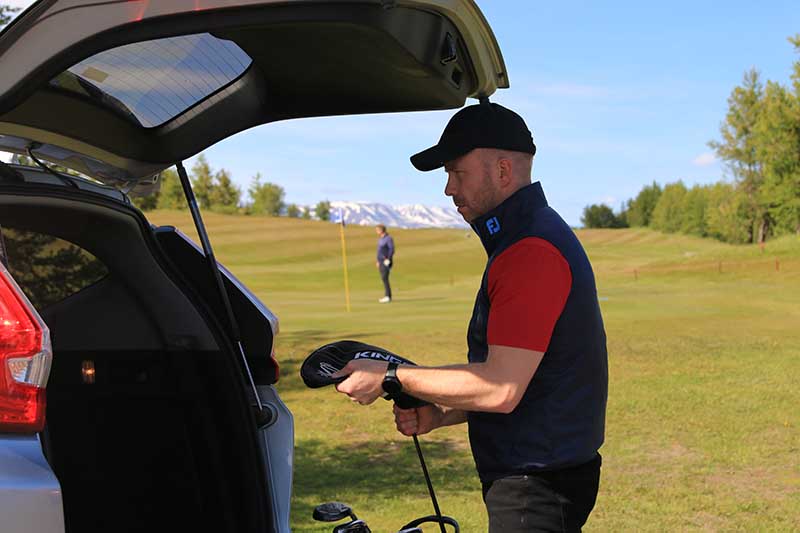 Icelandic golfer standing next to an SUV from Holdur car rental